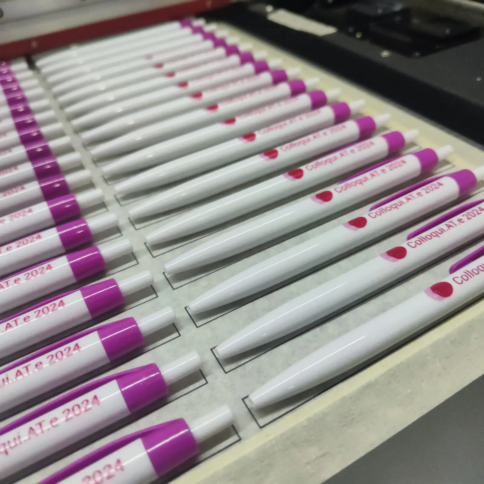 Produzione reale di penne bianche e fucsia personalizzate per un evento